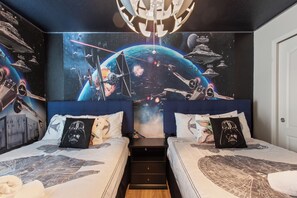 Ein Schlafzimmer mit zwei Betten, einem Wandgemälde zum Thema Star Wars und einer Deckenleuchte.
