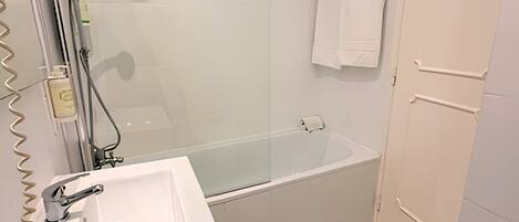 A bathroom with a glass-enclosed shower, a white sink, and a toilet.