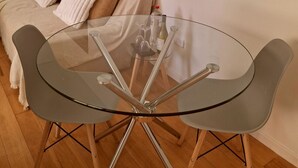 A glass-top dining table with metal legs, a beige sofa with cushions, and a white wall. - Oceanfront Apartment Estudio el Suspiro (Tunquen)