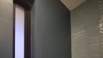 Un baño con inodoro, ventana y pared con azulejos.