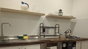 A kitchen with a stainless steel sink, a dish rack, a kettle, and a dishwasher. - Oceanfront Apartment Estudio el Suspiro (Tunquen)