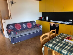 A compact living space with a sofa, dining table, and kitchen area. - Apartment "Casa dai Nonni" Cozy apartment with beautiful lake view (Perledo)