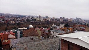 A cityscape with a mix of residential and commercial buildings, including a prominent tower. - Room N 6 by Kraveli (Tbilisi)