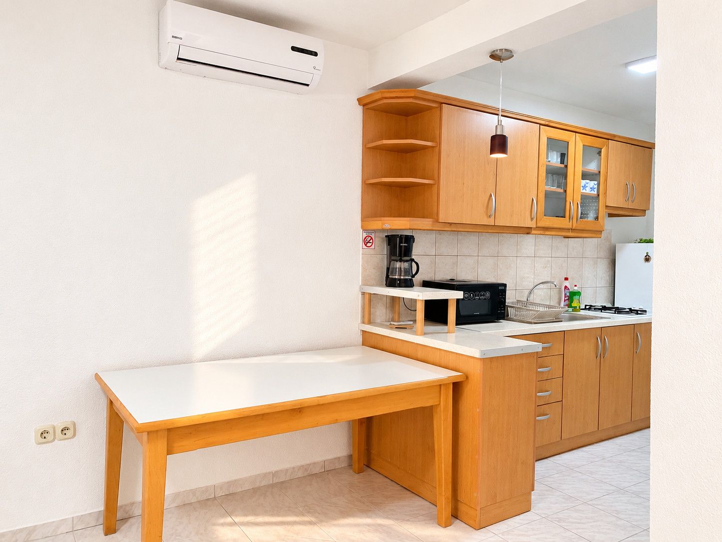 A compact kitchen with wooden cabinets, a built-in stove, and a small dining table.