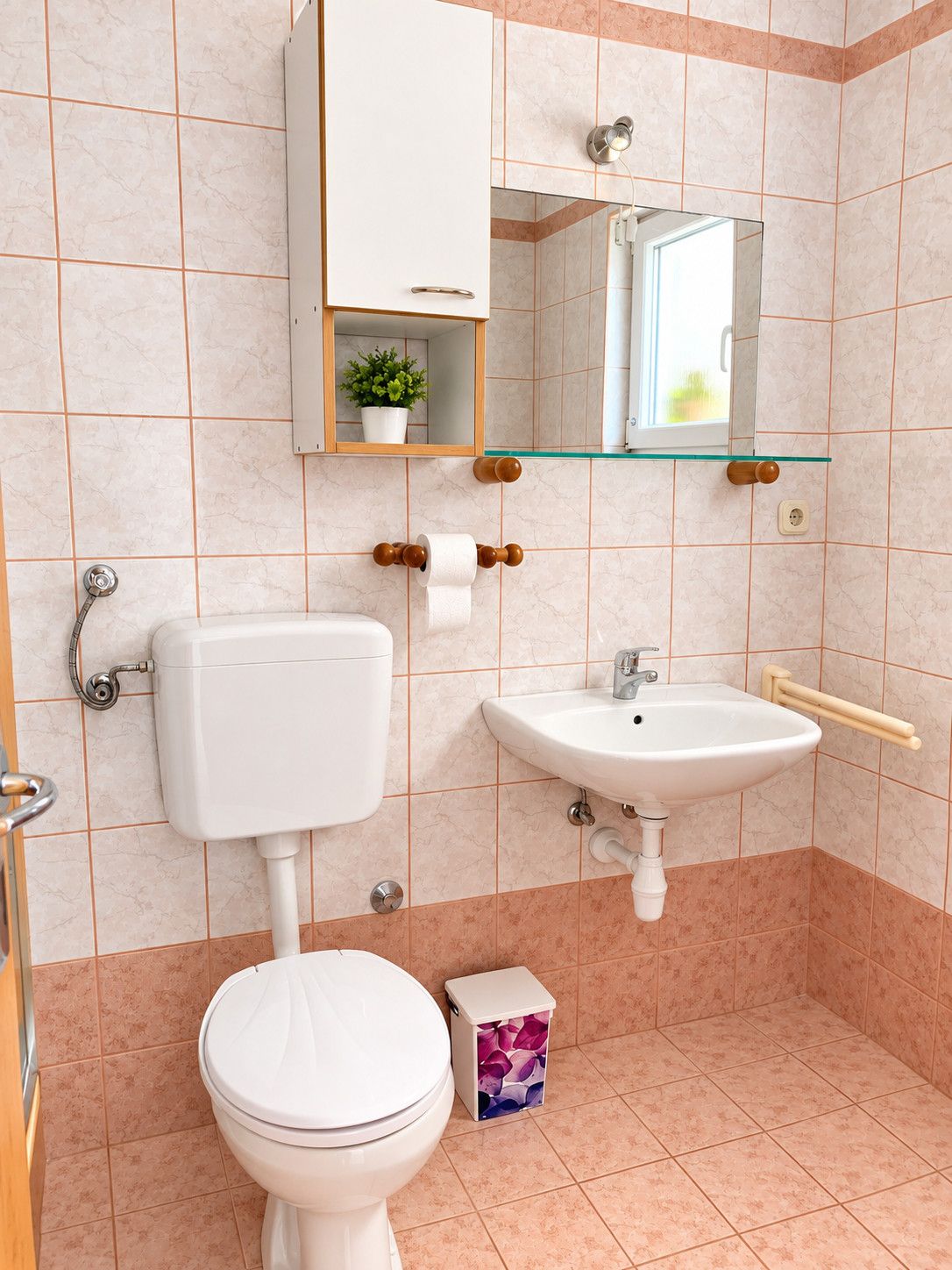 A bathroom with a toilet, sink, and mirror.