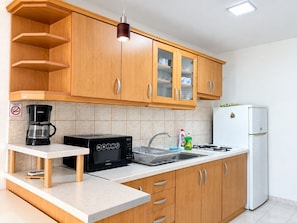 A kitchen with wooden cabinets, a coffee maker, a microwave, a sink, and a white refrigerator. - Apartment Vir 1 (Vir)