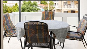 Un espace extérieur aménagé, abrité et doté d’une table et de chaises, de grandes fenêtres et d’une vue sur les bâtiments et la verdure.