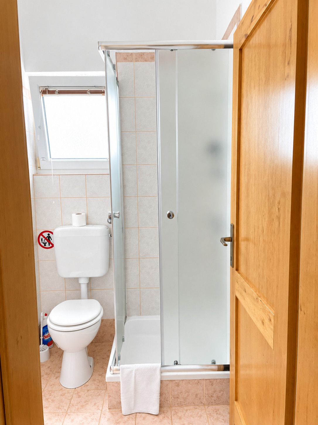 Une salle de bain comprenant des toilettes, un espace douche et une porte en bois.