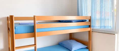 A bunk bed with blue bedding and a window with blue curtains.
