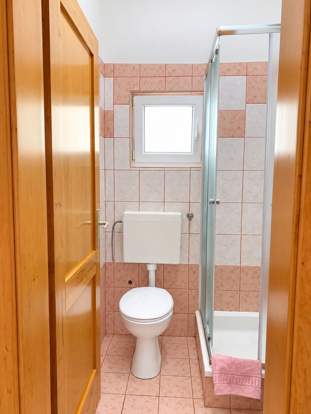 Une salle de bain avec des toilettes, une douche et une fenêtre.