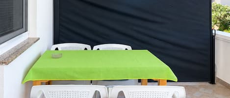 A balcony with a table and chairs, a black privacy screen, and an air conditioning unit.