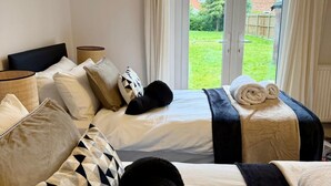 Ett hotellrum med två sängar, ett stort fönster med gardiner och utsikt över omgivningarna.