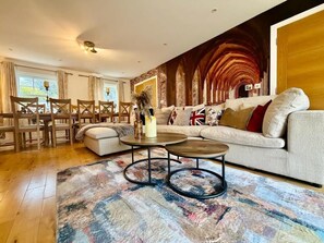 Un salon moderne comprenant un canapé, deux tables basses et un coin repas avec des chaises.