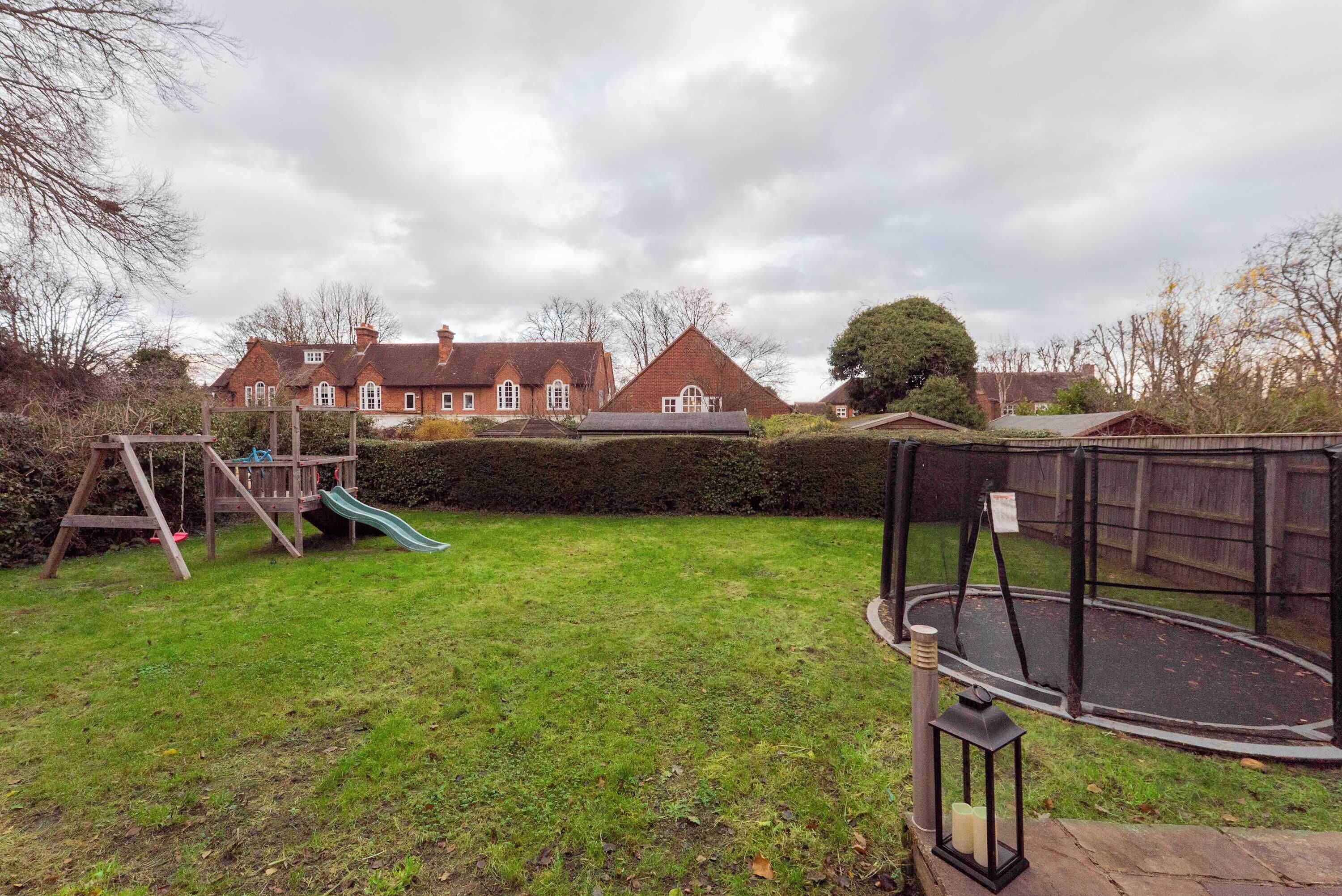 A backyard with a wooden playset, a trampoline, and a swing set.