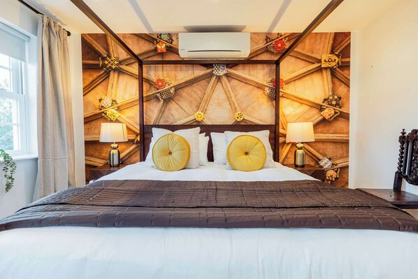 Une chambre d’hôtel avec un grand lit, une tête de lit en bois et un ventilateur de plafond.