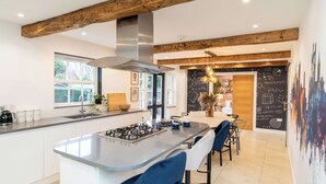 Una cocina moderna con una isla central, taburetes de bar y una pared de pizarra con ecuaciones matemáticas.