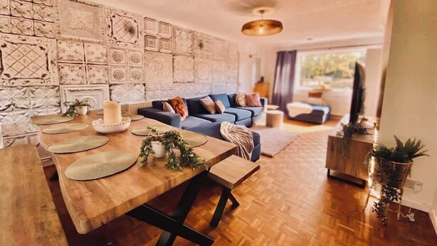 Un salon moderne avec une table à manger en bois, un canapé bleu et des œuvres d’art décoratives accrochées au mur.