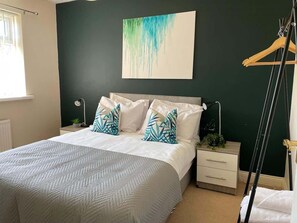 A bedroom with a bed, nightstands, a wall-mounted artwork, and a window. - Stunning ELY House - Perfect Retreat for Large Groups (Cambridgeshire)
