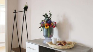 Un escriptori amb un ram de flors, una tassa i una cistella de petits berenets.