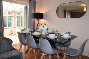 A dining area with a table set for four, surrounded by grey chairs, a black lamp, and a mirror on the wall. - Stunning ELY House - Perfect Retreat for Large Groups (Cambridgeshire)