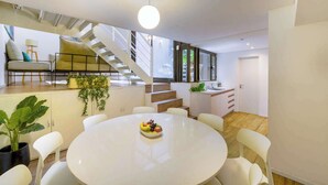 Un ambiente moderno con zona pranzo, cucina e scala.