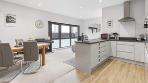 Una cocina moderna con armarios blancos, estufa integrada y un comedor con piano.