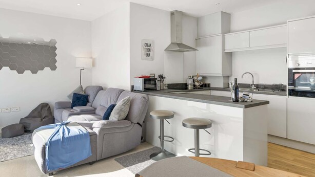 Un apartamento moderno con sala de estar, cocina y un pequeño espacio bar.
