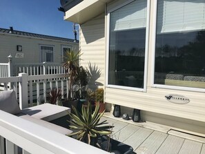 Une terrasse blanche avec une balustrade blanche, des plantes en pot et une fenêtre ornée d’une enseigne indiquant « Villerby Holiday Homes ».