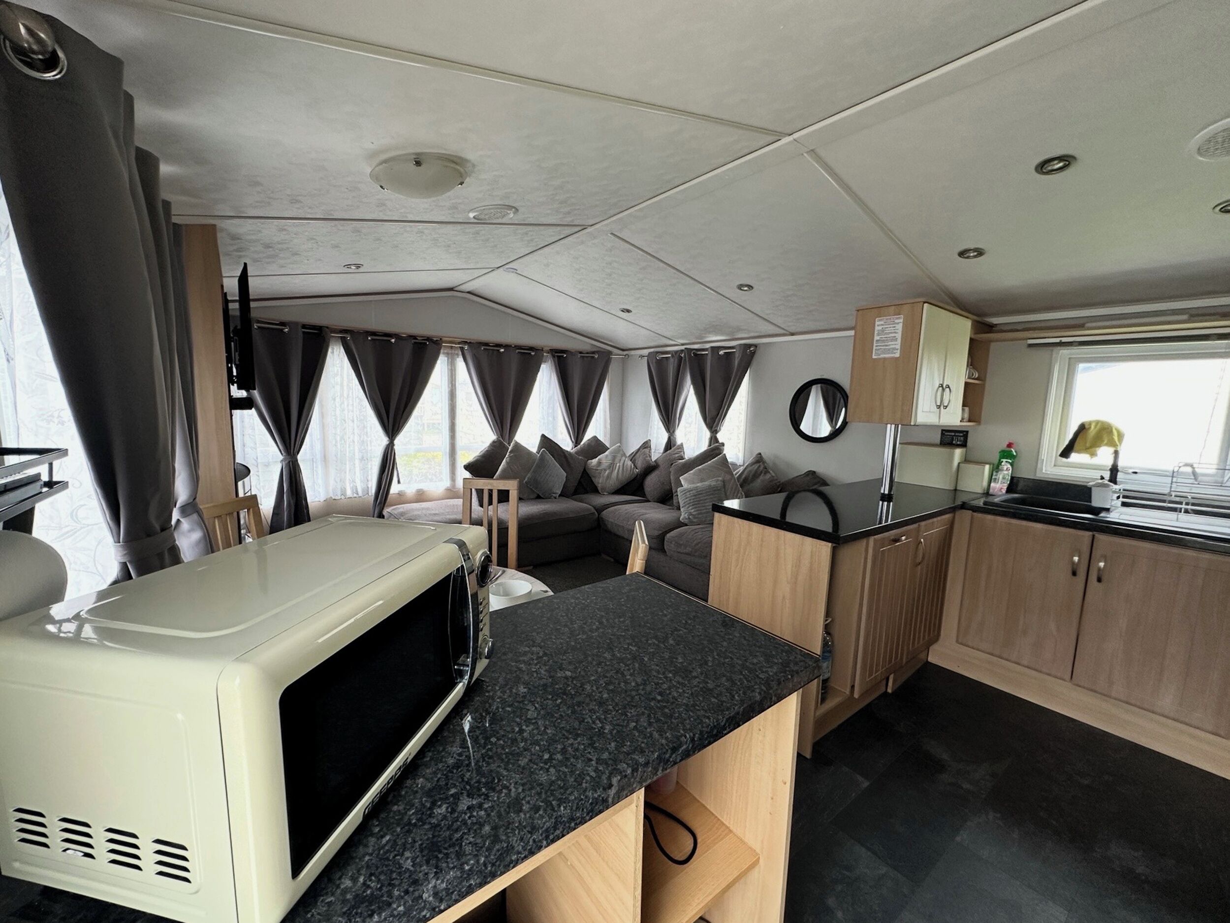 Een compact RV-interieur met een kitchenette, een zithoek met kussens en een klein tafeltje.
