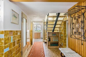 Un couloir avec un escalier en bois, une étagère remplie de bouteilles et un tableau encadré accroché au mur.