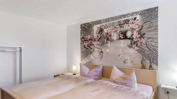 Ein Schlafzimmer mit einem Bett, einem Nachttisch, einer Wandlampe und einem dekorativen Wandbild.