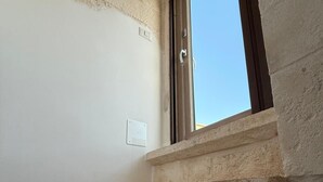 Un escalier en pierre menant à une fenêtre d’où l’on peut admirer le ciel.