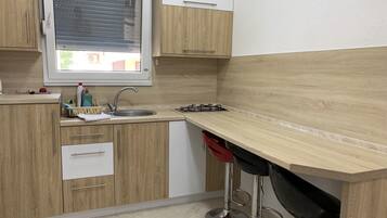 A modern kitchen with wooden cabinets, a sink, a window, and a bar stool.