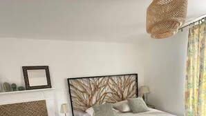 A bedroom with a wooden floor, a bed with a dark headboard, a bedside table with a lamp, and a hanging light fixture. - French Countryside Retreat With Jacuzzi (Plouasne)