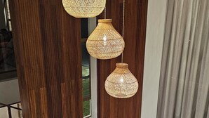 A room with a wooden wardrobe, a sliding door, and a hanging rattan light fixture. - Luxury house in contact with nature and private pool in Praia do Forte (Açu da Torre)