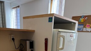 Una kitchenette compacta con un refrigerador blanco, un tostador y un lavavajillas.