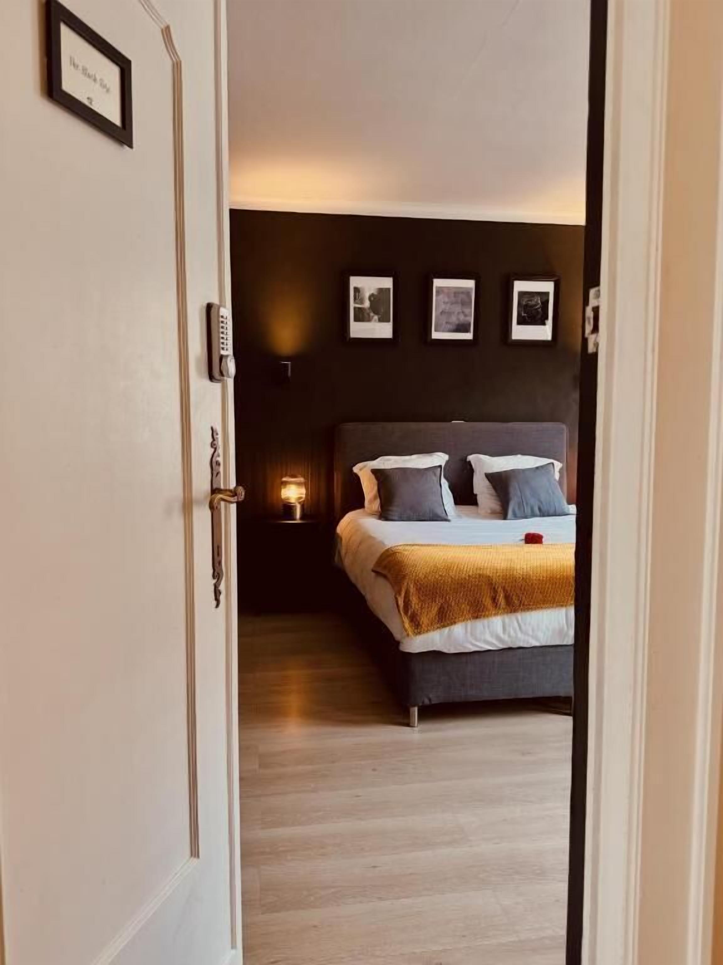 Een slaapkamer met een bed, nachtkastjes en foto's aan de muur.