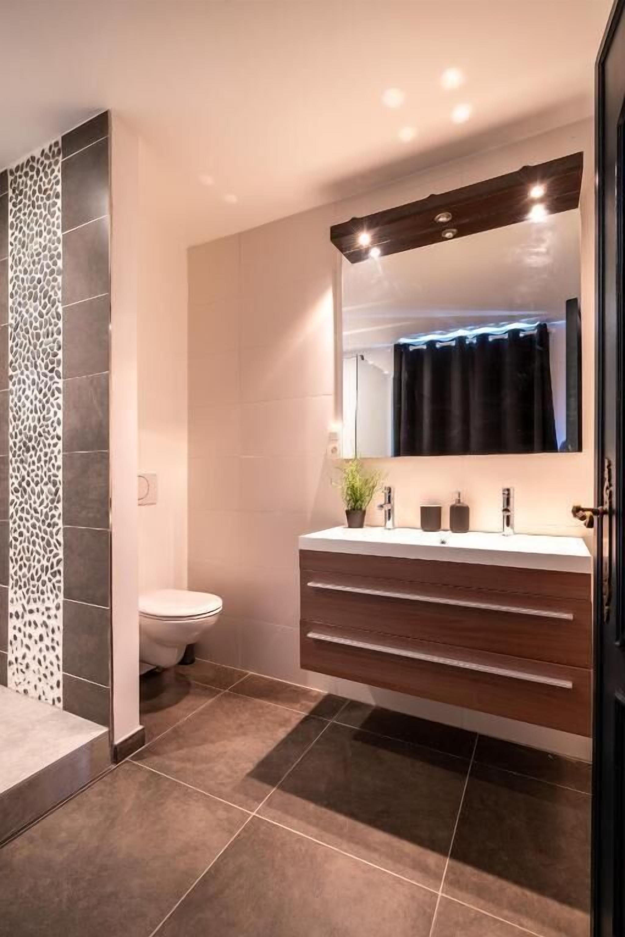Ein modernes Badezimmer mit Dusche, Toilette und Waschtisch mit Spiegel.