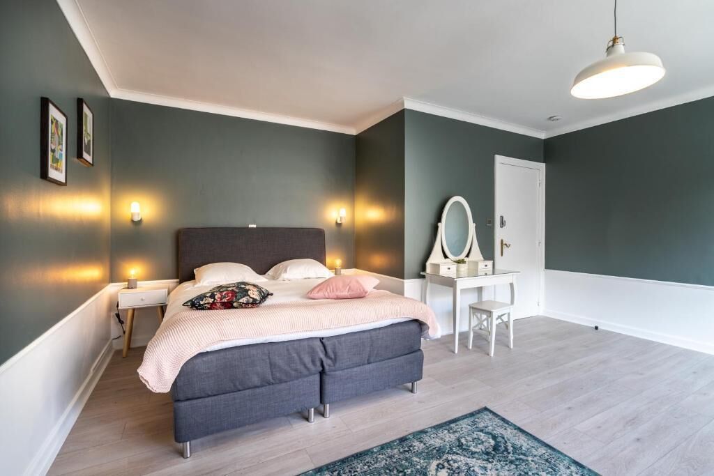 A modern bedroom with a bed, bedside tables, a dresser, and a mirror.