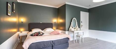 A modern bedroom with a bed, bedside tables, a dresser, and a mirror.