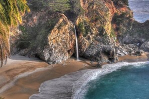 A coastal landscape with a waterfall, rocky cliffs, and a sandy beach. - Private Coastal Retreat Near Monterey Bay & Beach! (Marina)