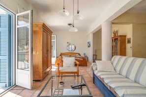 A room with a glass coffee table, a sofa, a wooden cabinet, and a bed with a headboard. - Studio Apartment 'Pilali 1 Greece' with Balcony, Wi-Fi and Air Conditioning (Agia Effimia)
