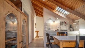 Una cocina con armarios de madera, una mesa de comedor, sillas y un tragaluz.