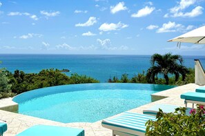 A clear blue pool with a view of the ocean, surrounded by greenery and lounge chairs. - Private 4BR Oceanview Villa - Private Pool - Peaceful Hilltop Setting (Crab Hill)