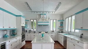 Une cuisine spacieuse avec des meubles blancs, un îlot central et un lustre.