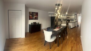 Una cocina moderna con una isla central, suelo de madera y un comedor con una silla blanca y una mesa.
