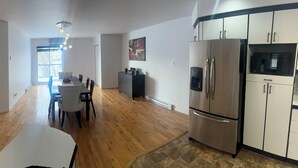 Una cocina moderna con refrigerador, microondas y comedor con mesa y sillas.