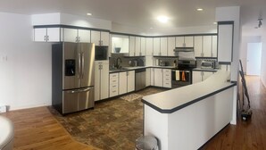 Una cocina moderna con electrodomésticos de acero inoxidable, armarios blancos y suelo de madera.