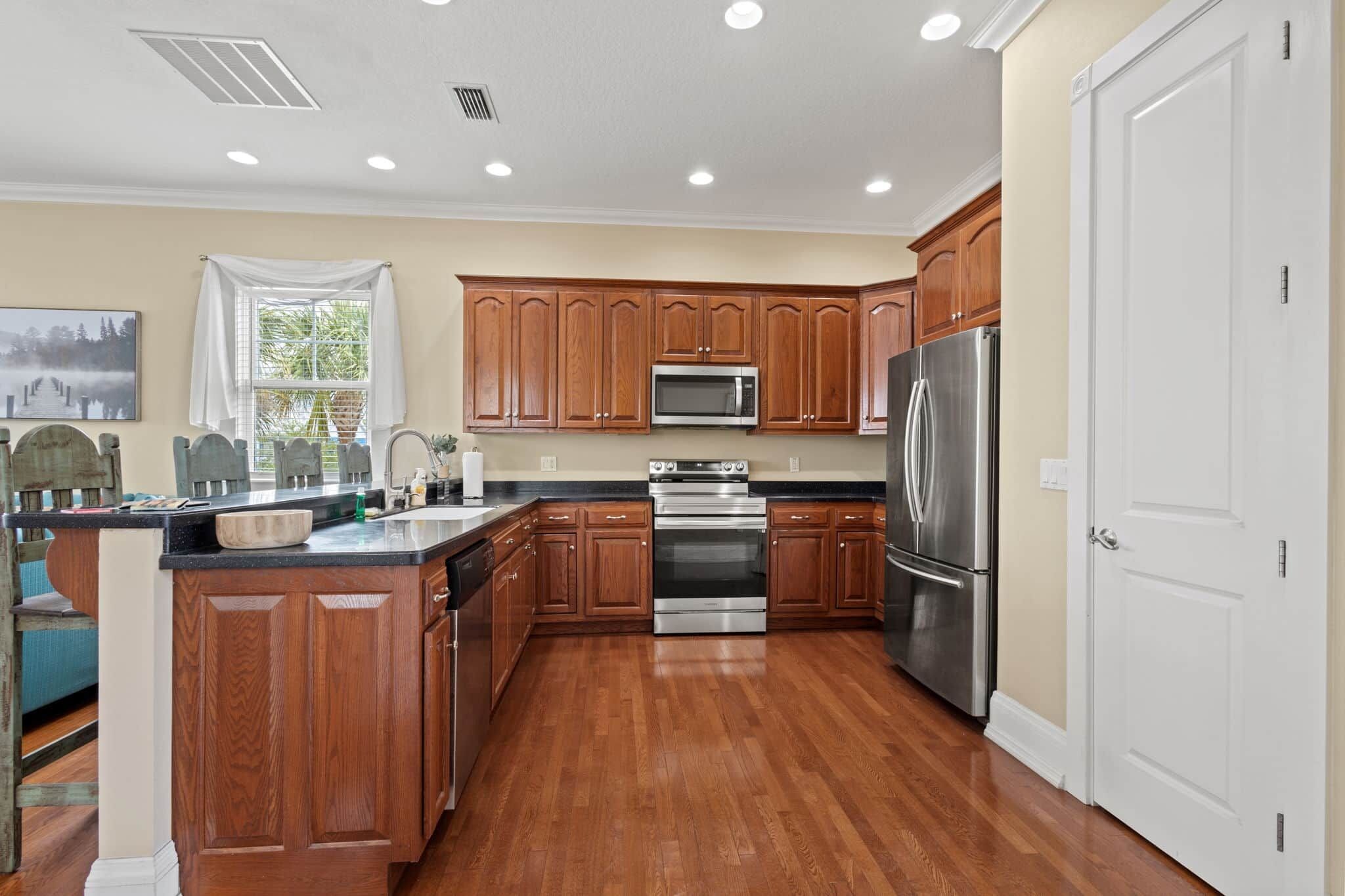 A kitchen with wooden cabinets, stainless steel appliances, and a wooden floor.