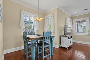 A dining area with a wooden table and chairs, a chandelier, and a television on a white cabinet. - Driftwood Haven at Rivers Bend - Steinhatchee (Steinhatchee)